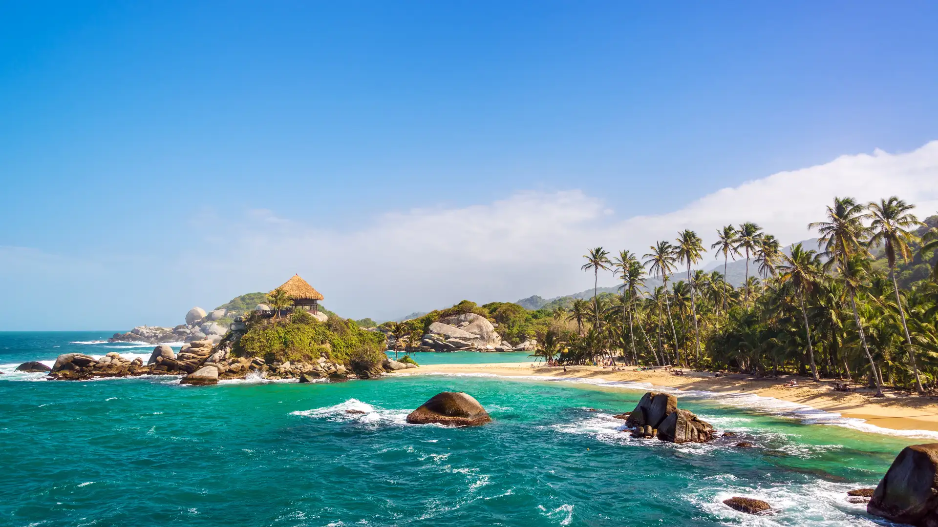 Playa del Parque Tayrona con palmeras, rocas y mar turquesa